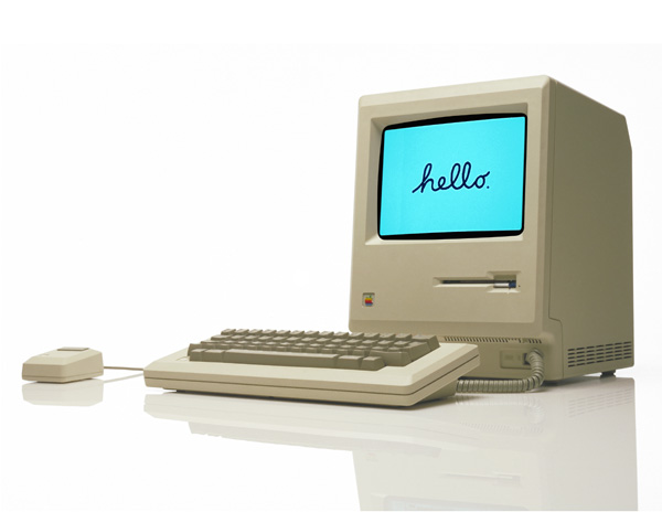 The first Macintosh computer, the 128k, on a white reflective surface.
